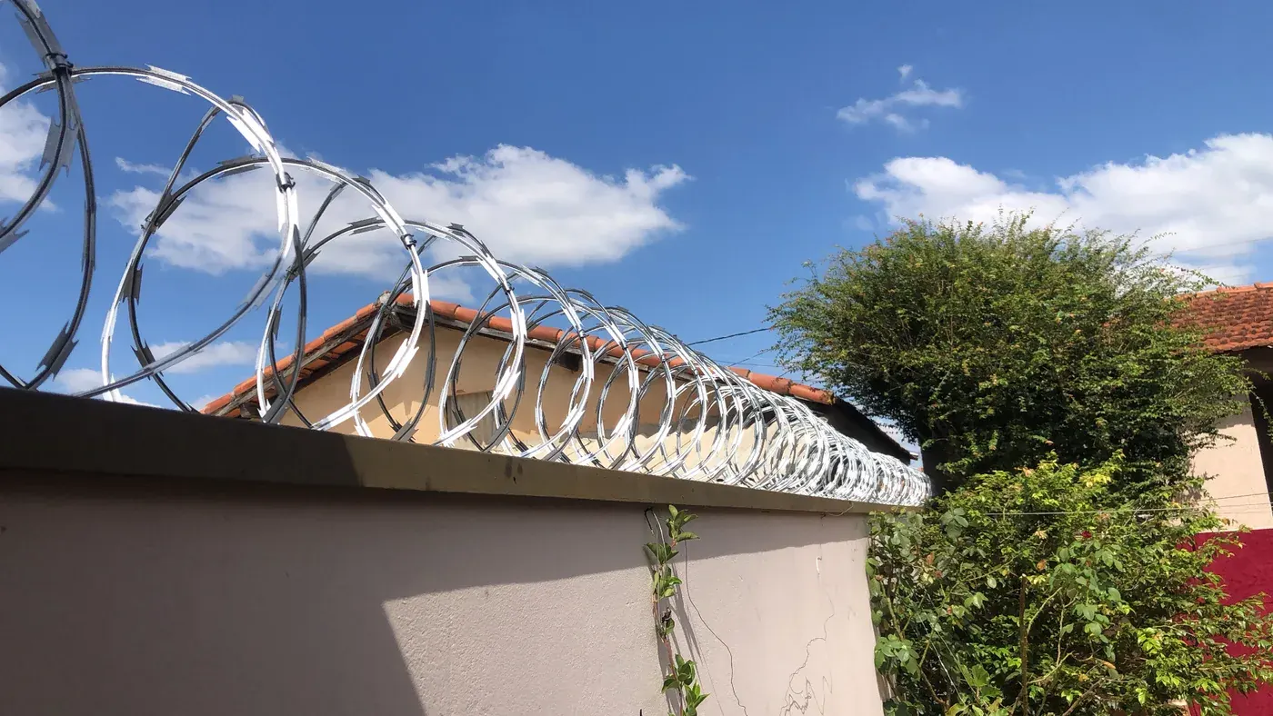 Vista lateral das espirais de concertina instaladas sobre um muro branco